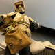 A toy Imperial Scout Trooper prepares to punch a toy Baby Yoda stuffed in a sack.